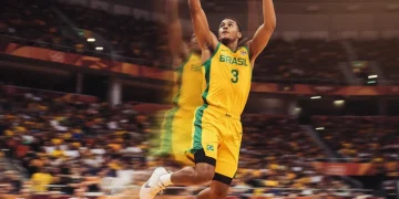 Jogador de basquete saltando para pegar um rebote em quadra indoor.