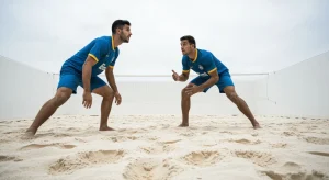 Dois jogadores de futevôlei masculinos em posicionamento defensivo estratégico na areia, demonstrando comunicação visual e tática em quadra.