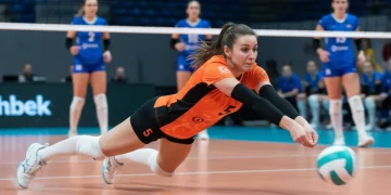 Líbero de vôlei em ação, realizando uma defesa espetacular em quadra