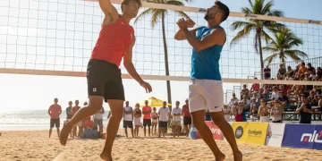 Footvolley players spiking ball over net on beach court