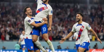 Dynamic US soccer forwards celebrating a goal during a match, showing teamwork and excitement.