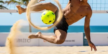 Dynamic footvolley player launching a powerful back-row attack on a sunny beach court.